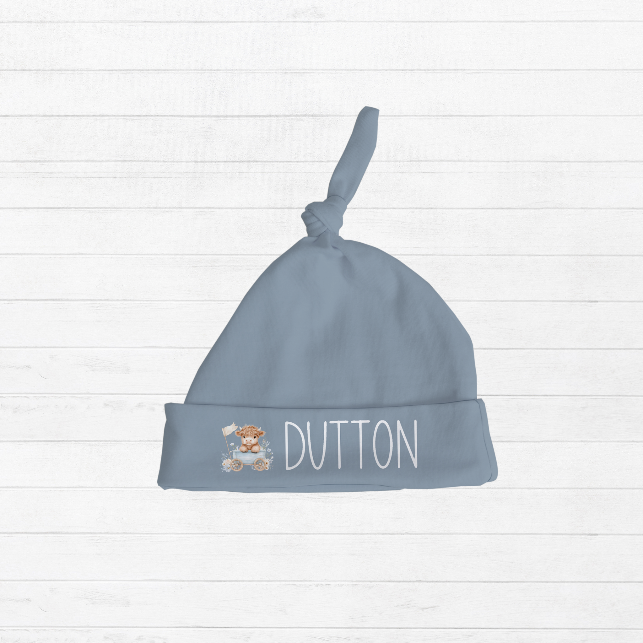 Personalized blue knotted newborn hat with Highland Cow design and baby name