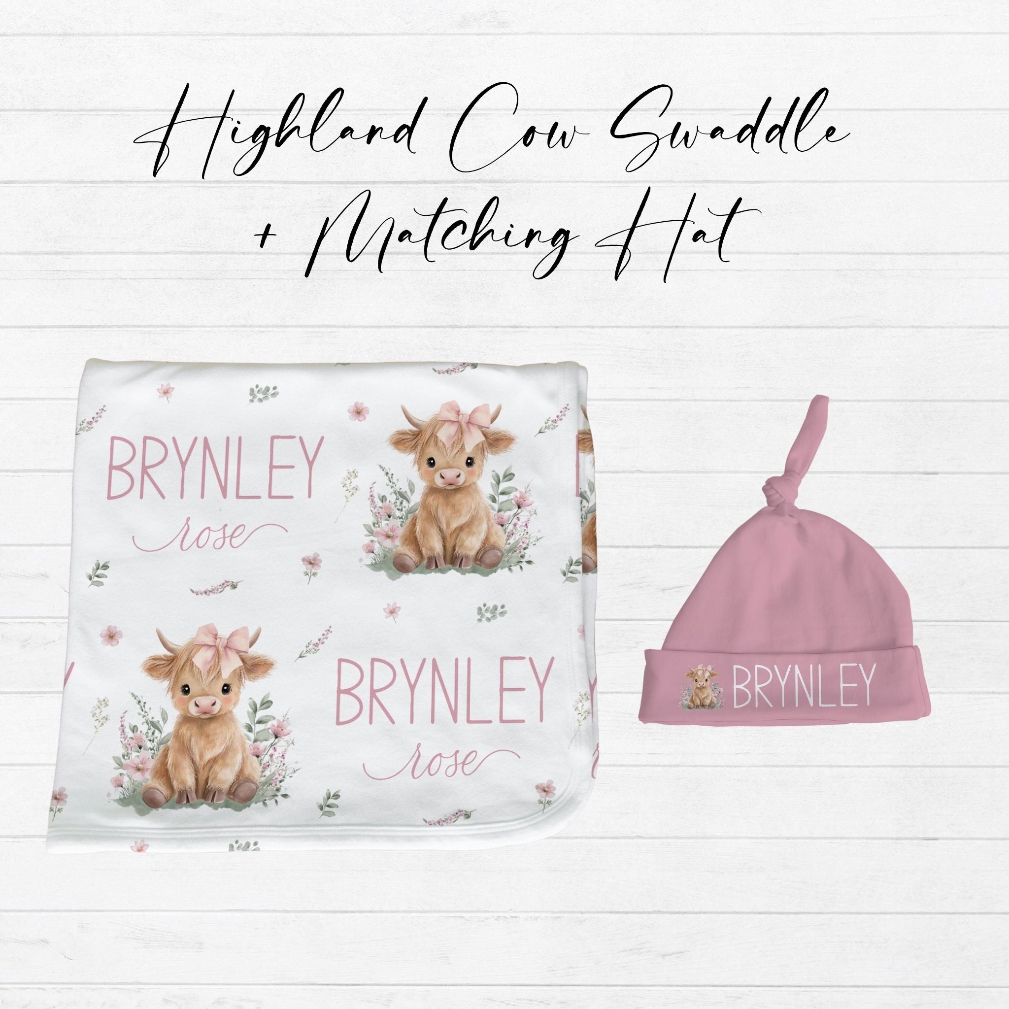 Highland cow pink baby swaddle and matching hat set flat lay showing white swaddle with pink highland cow design and coordinating pink knotted hat with custom name