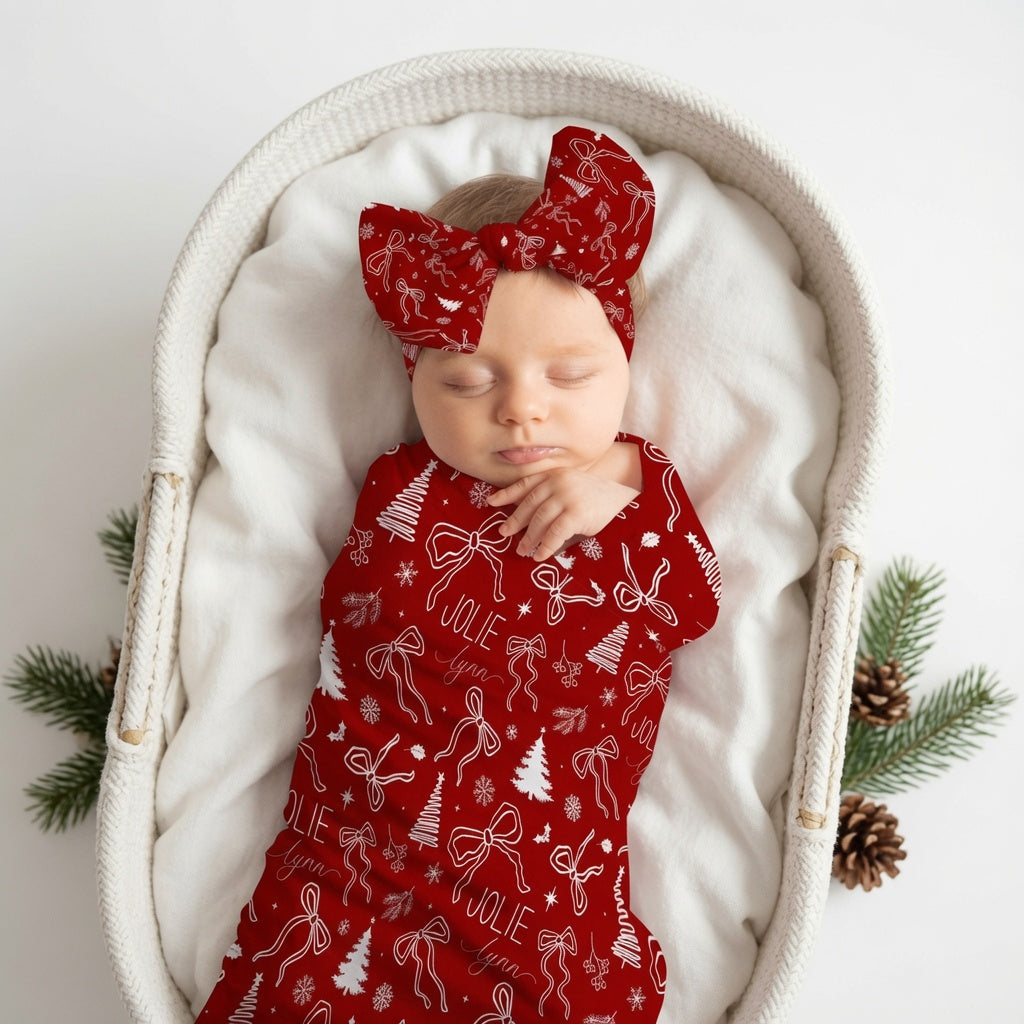 Newborn baby wearing personalized Christmas bows swaddle and matching headband with custom name — Twinklette holiday baby gift set