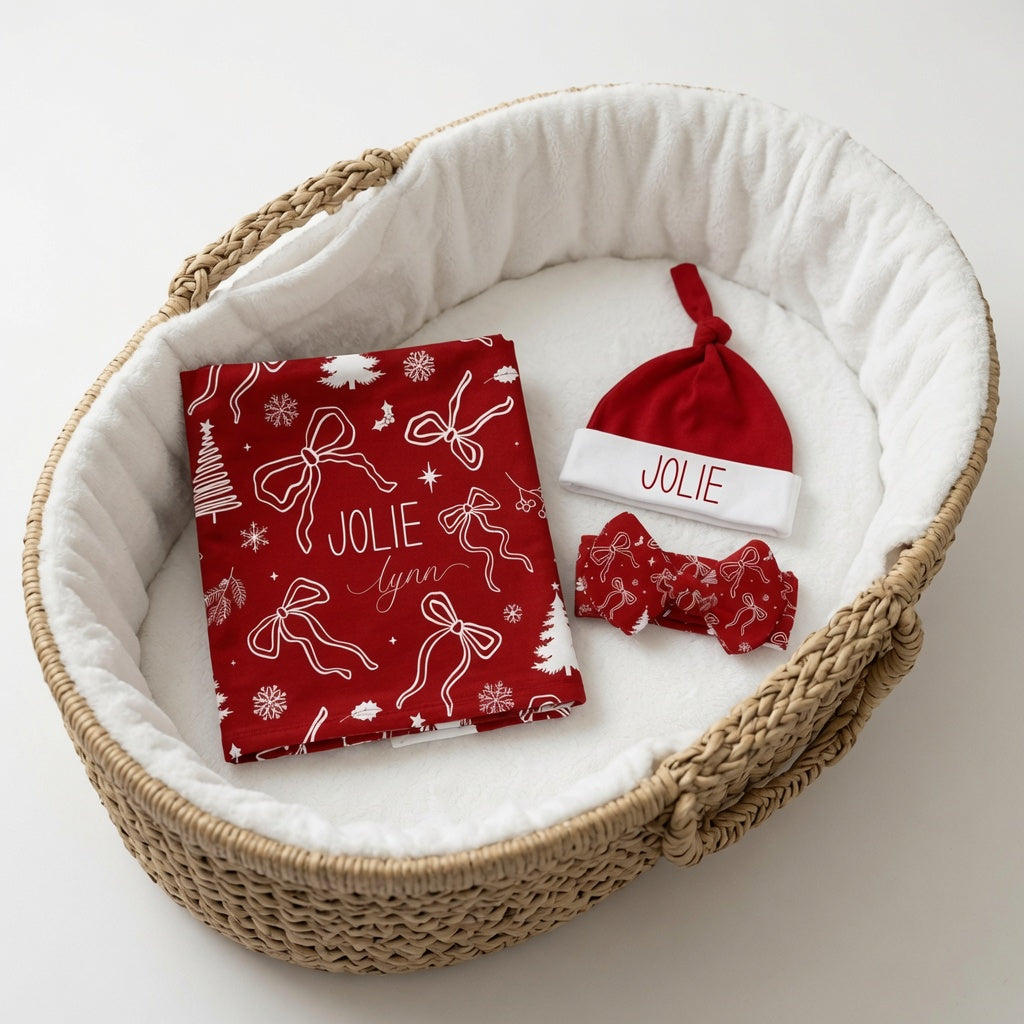 Personalized Christmas Bows Baby Matching Set - baby swaddle, headband, and knotted hat set in red, displayed in a Moses basket — custom name newborn gift set by Twinklette
